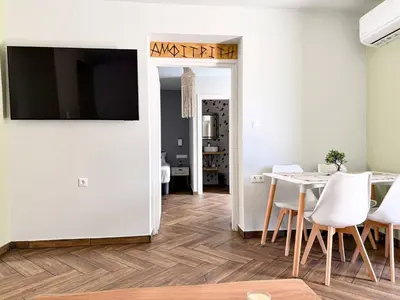 a dining room with a table and a television on a wall at Amfitriti 30meter to beach, 6min Old Town, 2BD 4PL in Chania Town