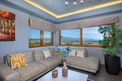 a living room with a couch and large windows at Villa Lady Dafni with private heated pool in Maleme