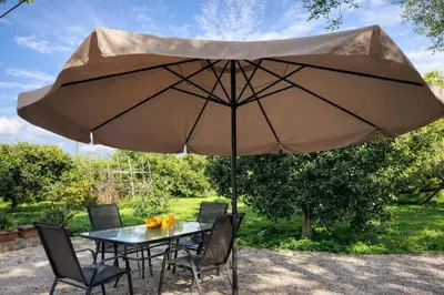 a table and chairs under a large umbrella at Mersini Village in Milonianá