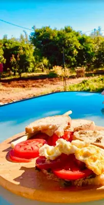 a sandwich on a cutting board with a tomato on it at Mersini Village in Milonianá