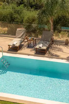 two chairs and a table next to a swimming pool at Mystique Villa by Vintage Travel in Tavronitis