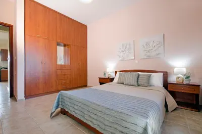 a bedroom with a large bed and wooden cabinets at Villa Alimedon in Almirida