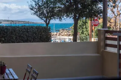 a stop sign and a table and chairs in front of the ocean at A&G mare in Chania Town