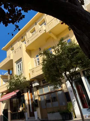 a large yellow building with trees in front of it at Deluxe Center Suites in Chania Town