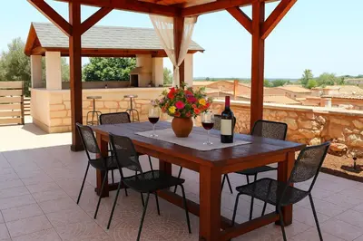 a wooden table with wine glasses and a vase of flowers at Chania's Diamond Villas - Aqua Bliss with Private Pools in Gavalochori