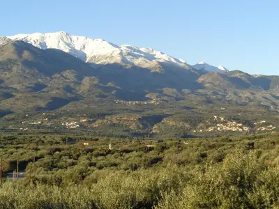 a snow covered mountain in the distance with trees at Apartment in natural stone house in Spiliá