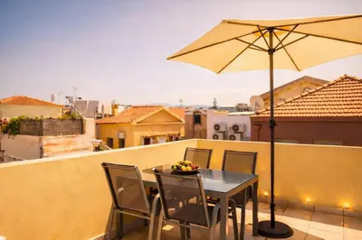 a table and chairs with an umbrella on a balcony at Gardenia Maisonette Rooftop Old Town View in Chania Town