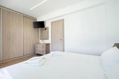 a bedroom with a white bed and a wooden cabinet at Villa Sea Breeze in Xamoudhokhórion