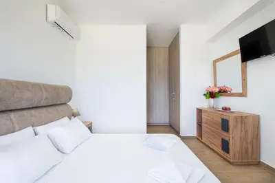a bedroom with a white bed and a television at Villa Sea Breeze in Xamoudhokhórion