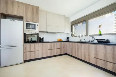 a kitchen with wooden cabinets and a white refrigerator at Villa Sea Breeze in Xamoudhokhórion