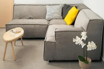 a grey couch with a yellow pillow and a table at Ethea Residences-Helia in Chania Town
