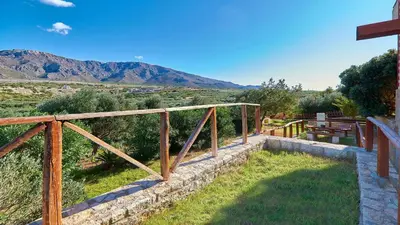 a wooden bridge over a field with mountains in the background at La Irilia Residences & Retreat in Agios Padeleimon