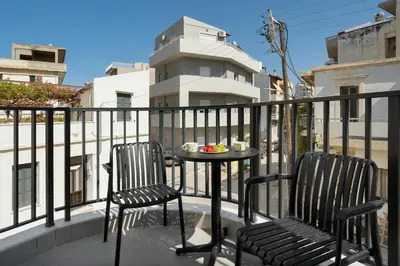 a balcony with two chairs and a table with food on it at Coralie 3 bedroom apartment 40m from the beach in Chania Town