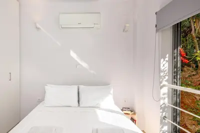a white bedroom with a bed and a window at Central cozy garden flat in Chania Town