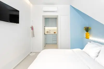 a bedroom with a white bed and a television at Αthena Studio 3 in Chania Town