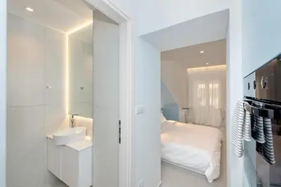 a white bathroom with a sink and a bed at Αthena Studio 3 in Chania Town