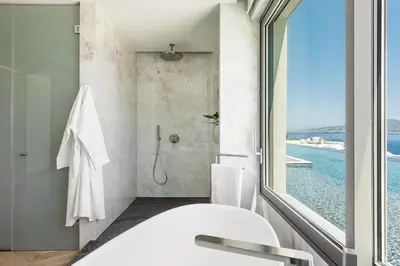 a bathroom with a tub and a shower with a window at Only View Villa - Timeless Coastal Retreat by etouri in Chania