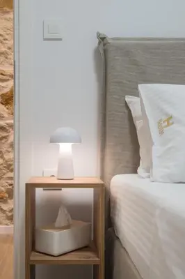 a bed with a night stand with a lamp on it at Hanim 2BR Loft Apartment - Garden & Indoor Parking in Chania Town