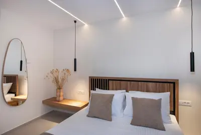 a bedroom with a bed with white pillows and a mirror at Bōw Ground Floor Luxury Apt-In Chania Old Town! in Chania Town