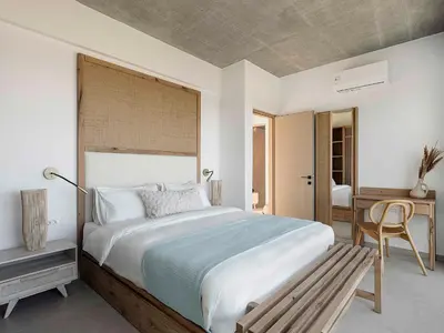 a bedroom with a large bed and a wooden bench at Himmel Villas - Seaview luxury & private pools in Kalivianí