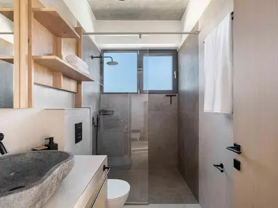 a bathroom with a shower and a sink and a toilet at Himmel Villas - Seaview luxury & private pools in Kalivianí