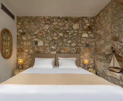 a bedroom with a bed and a stone wall at Omorphi Seaside Villa in Kalyves