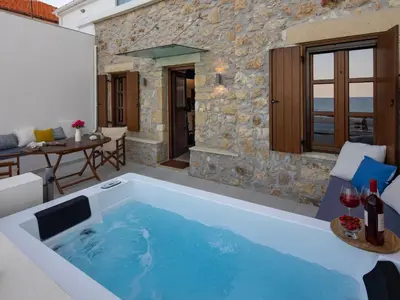a hot tub in a patio with a table and chairs at Omorphi Seaside Villa in Kalyves