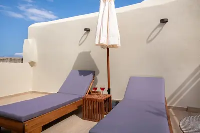 a room with a bed and an umbrella and a table at BŌW 2nd Floor Luxury Apt -Heart of Chania Old Town in Chania Town