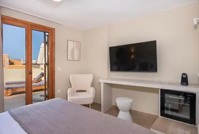 a bedroom with a bed and a tv and a chair at BŌW 2nd Floor Luxury Apt -Heart of Chania Old Town in Chania Town
