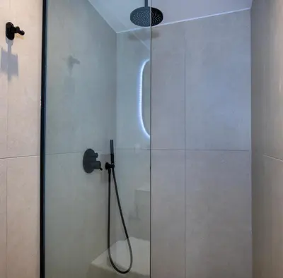 a shower with a glass door in a bathroom at BŌW 2nd Floor Luxury Apt -Heart of Chania Old Town in Chania Town