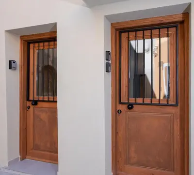two wooden doors in a room with a window at BŌW 2nd Floor Luxury Apt -Heart of Chania Old Town in Chania Town