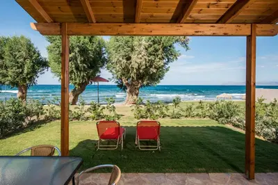 a patio with chairs and the ocean in the background at Lila Villas in Stalos
