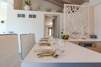 a white kitchen with a table with plates and silverware at Seawhisper Villa in Kalyves