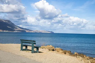 a green bench sitting on the shore of a body of water at Agapi in Kissamos