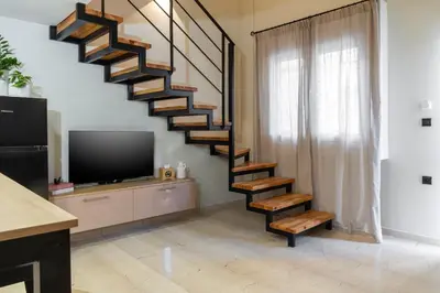 a spiral staircase in a living room with a tv at La Petite Fleur City apartment Chania in Chania Town