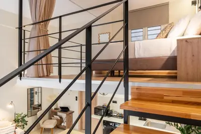 a loft apartment with a bed and a staircase at La Petite Fleur City apartment Chania in Chania Town