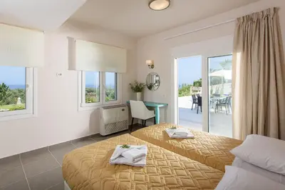 a hotel room with two beds and a balcony at Koukos Villas in Stalos