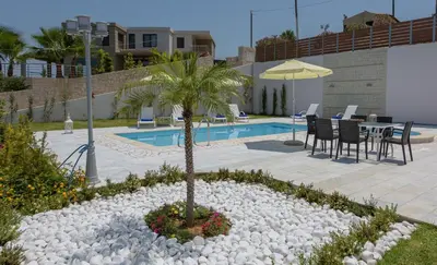 a garden with a palm tree and a pool at Koukos Villas in Stalos