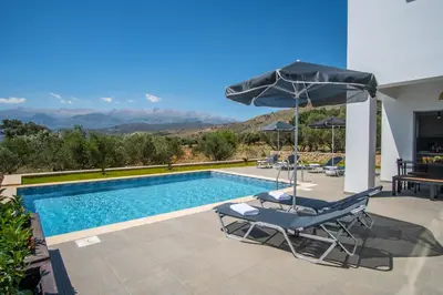 a swimming pool with two lounge chairs and an umbrella at Villa Alen in Áptera