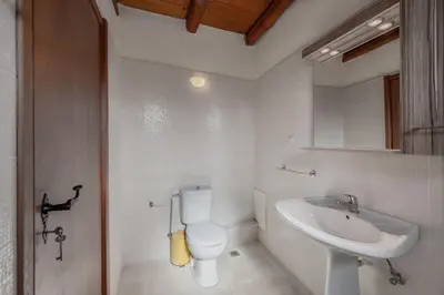 a white bathroom with a toilet and a sink at Vamos villa in Vamos