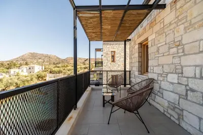 a balcony with a glass table and chairs on it at Villa Falcos by PosarelliVillas in Gavalochori
