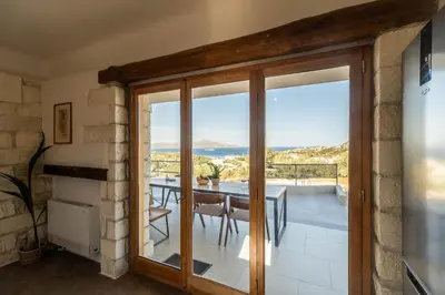 a dining room with a table and a view of the ocean at Villa Falcos by PosarelliVillas in Gavalochori