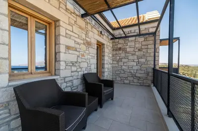 a balcony with two chairs and windows at Villa Seiri by PosarelliVillas in Gavalochori