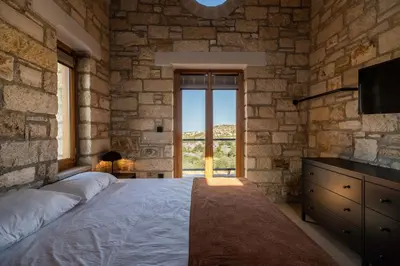 a bedroom with a bed and a stone wall at Villa Seiri by PosarelliVillas in Gavalochori