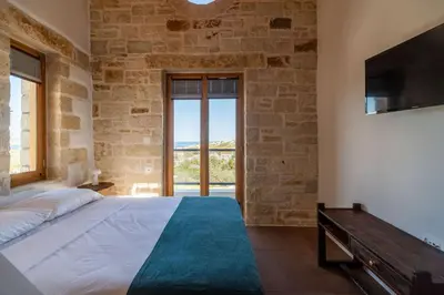 a bedroom with a large bed and a large window at Villa Lavidona by PosarelliVillas in Gavalochori