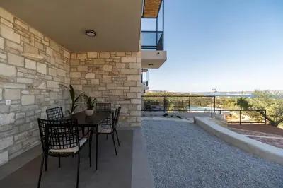 a patio with a table and chairs and a stone wall at Villa Lavidona by PosarelliVillas in Gavalochori