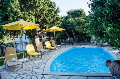 a swimming pool with chairs and umbrellas and a table at Villa Dimitris in Kalamitsi Amygdali