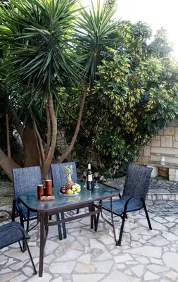 a table and chairs on a patio with palm trees at Villa Dimitris in Kalamitsi Amygdali