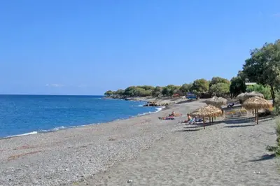 a beach with umbrellas and people sitting on the sand at Villa Olive Xrisi in Kafoúros