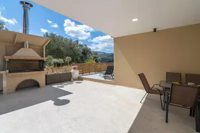a patio with a fireplace and a table and chairs at Huzuri Retreat in Kissamos
